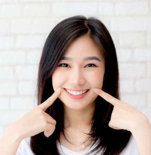 a woman pointing at her teeth and smiling
