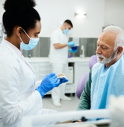 Dentist showing model teeth to patient 