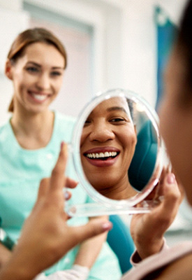 Patient smiling at reflection in treatment chair