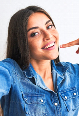 Smiling woman pointing to her white teeth