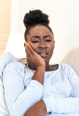 Woman with jaw pain sitting on couch at home