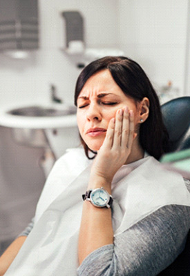 Woman with toothache sitting in treatment chair